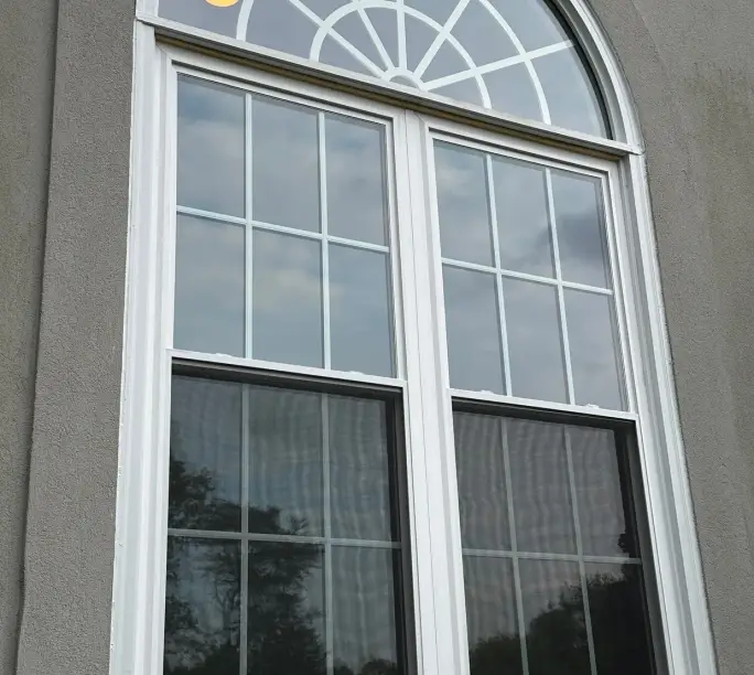 Arched double-hung with a fan transom, WowFix cap on the sill — a window built to outlive its builder warranty