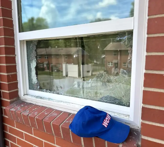 Shattered window pane on a brick Charlotte home before WowFix glass replacement — WowFix cap on the sill