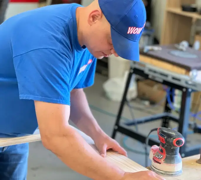 WowFix craftsman checking a fabricated replacement piece against the original window part