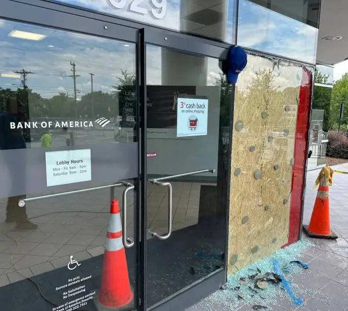 Shattered bank storefront door boarded up and coned off before WowFix emergency glass replacement