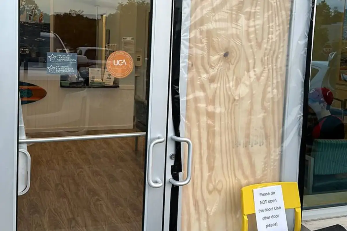 Clinic entrance door boarded up with plywood after the glass failed — secured by WowFix the same day