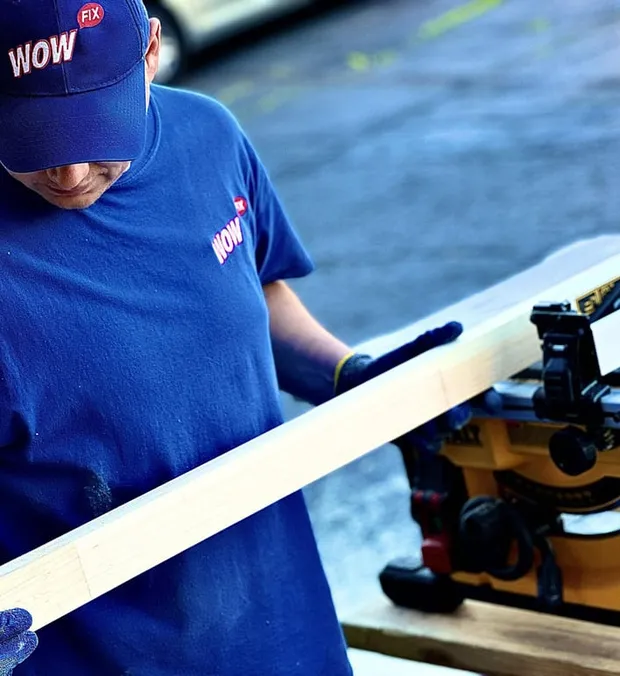 WowFix craftsman carrying milled lumber to the bench — repair stock for a Greensboro window