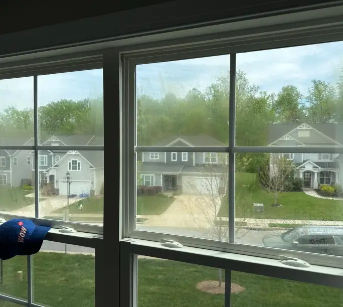 Two Raleigh double-hung windows side by side — the left one fogged by a failed seal, the right one clear
