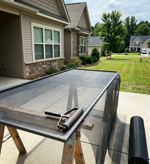 Screen mesh being rolled drum-tight during a WowFix visit in Greensboro