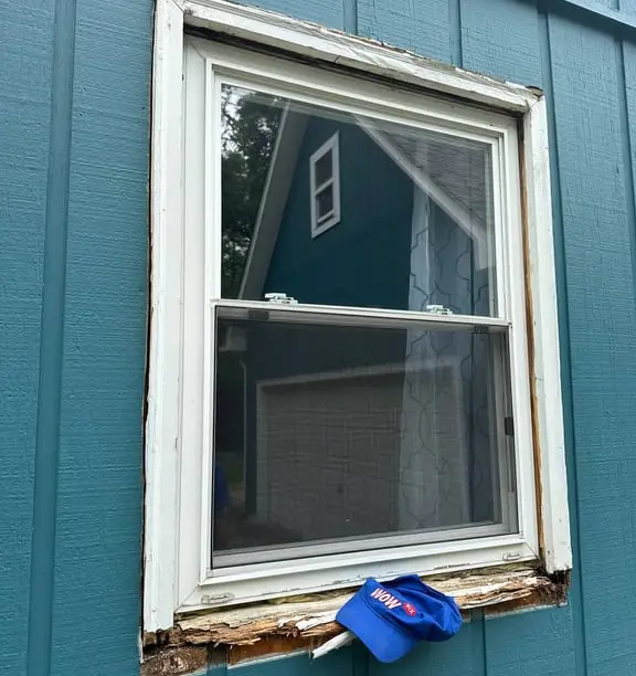 Window with rotted lower wood on a teal-sided home — WowFix cap in place