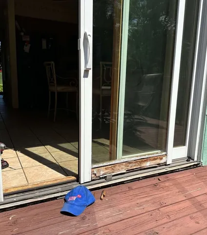 Sliding patio door with a rotted bottom rail mid-repair by WowFix — decay stripped back to sound wood, WowFix cap on the deck
