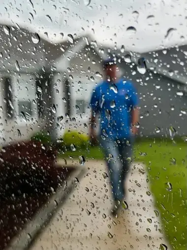 WowFix technician arriving through the rain — storm-season door call