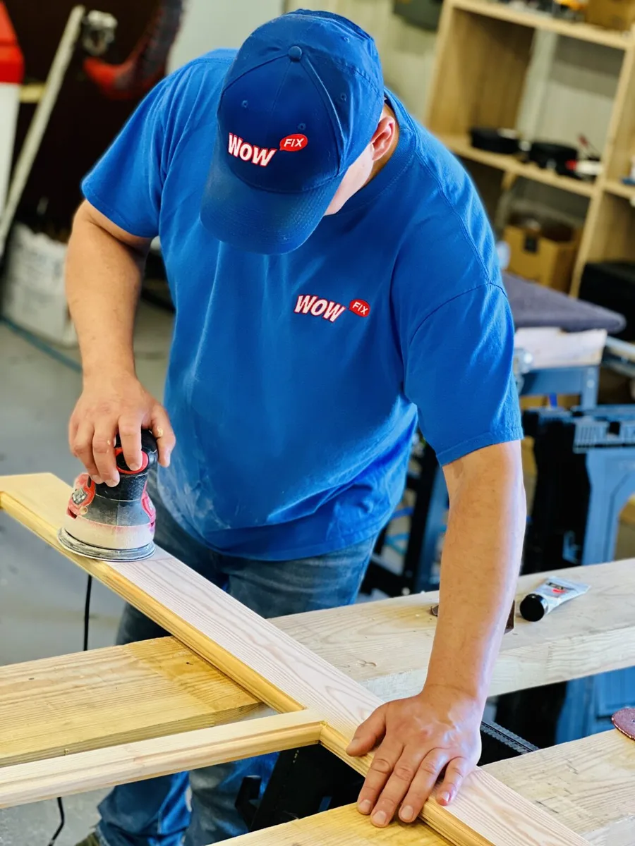 Eugene in WowFix blue sanding a fabricated repair piece at the workshop bench