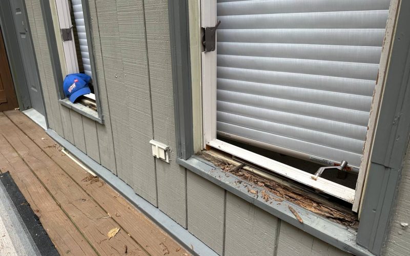 Deteriorating window frame with visible wood rot damage and worn siding, showcasing need for professional window repair services