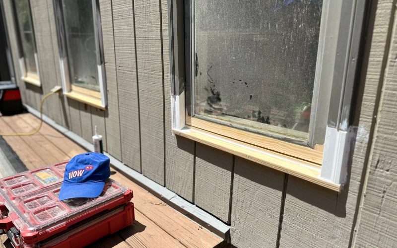 Window repair assessment showing moisture damage with WOW service cap and professional tools on wooden deck