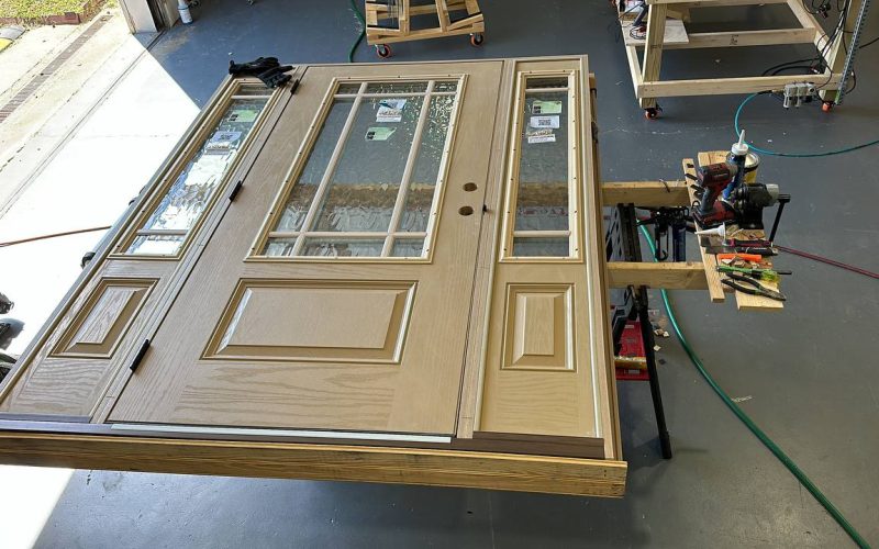 Custom craftsman entry door with decorative glass panels and sidelights being prepared for installation in Charlotte workshop