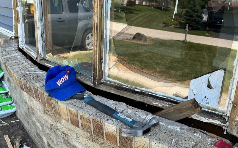 Severely damaged wooden window frame showing rot and deterioration, with repair tools on brick windowsill in Charlotte home