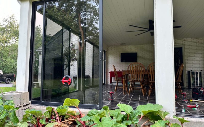 Large sliding glass patio door installation in modern brick home with interior dining room view and professional installation tools
