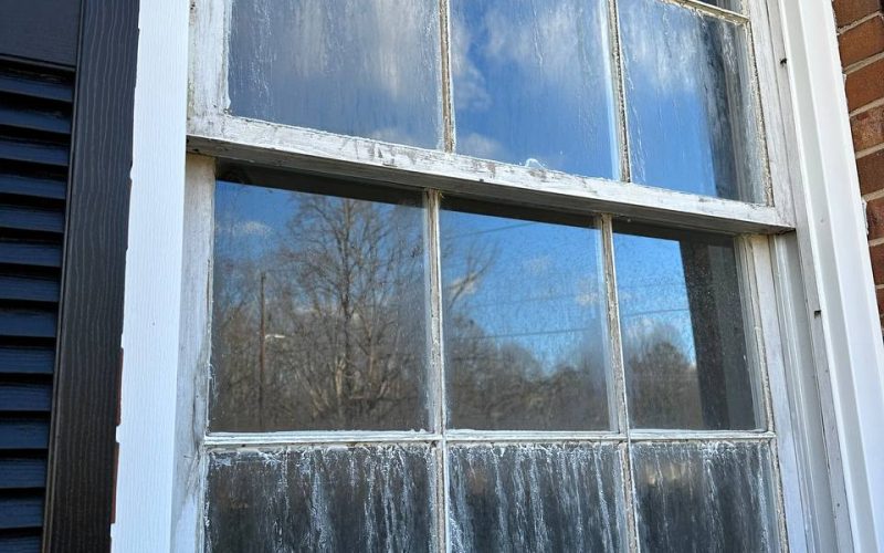 Foggy double-hung window with moisture damage and deteriorating frame, showing common window condensation issues needing repair