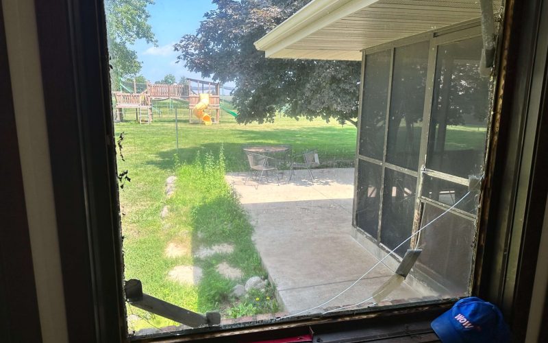 Damaged residential window screen and frame overlooking backyard playground, demonstrating need for professional window repair services