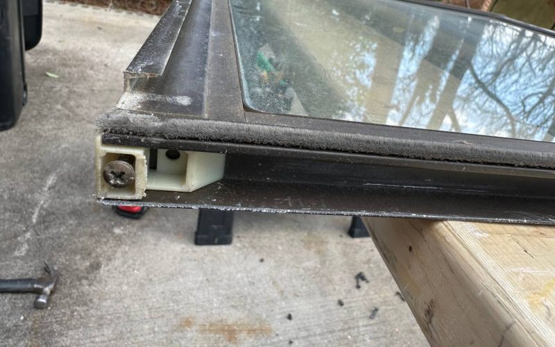 Detailed view of window frame assembly showing weatherstripping and mounting hardware requiring professional repair service