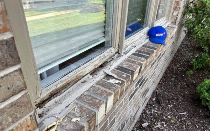 Severely damaged wooden window frame with rot and decay on brick home, demonstrating need for urgent window repair