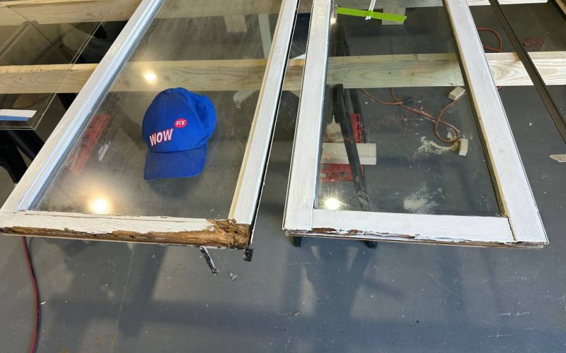 Damaged window frames with wood rot damage showing repair needs, with WOW FIX branded cap demonstrating before-repair condition