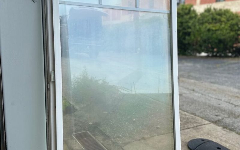 Commercial aluminum window frame with clear glass panel being prepared for installation, with WOW company branding visible