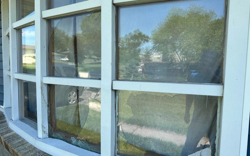 Severely damaged double-pane windows showing crack patterns in commercial window frame, demonstrating need for emergency window repair